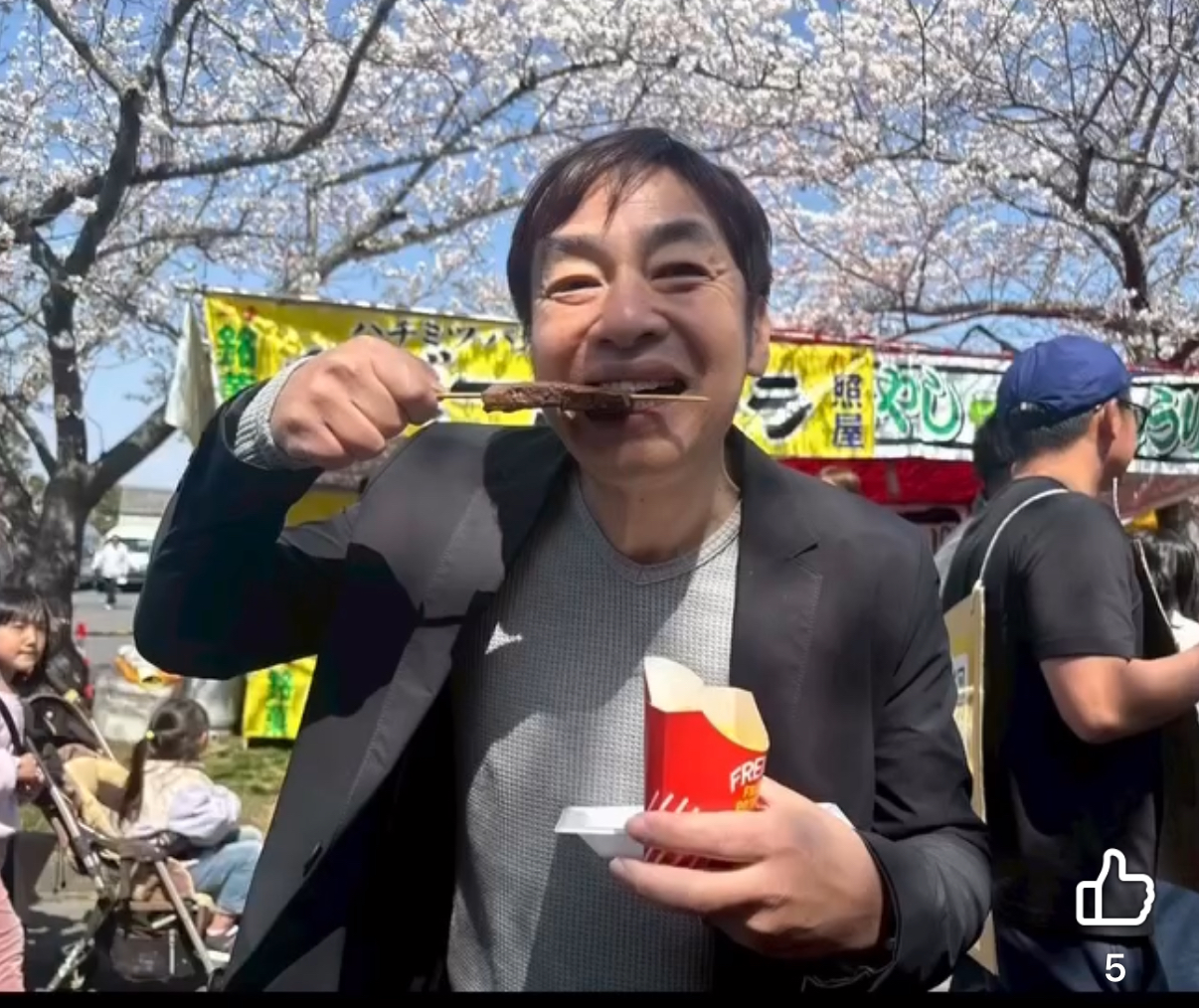 名張市の桜まつりにて牛串を頬張る名張市の議員小林勝